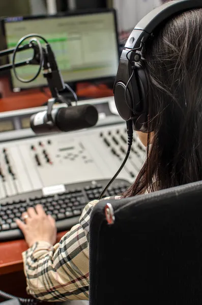 Anchorwoman zit een microfoon op de radio, vanaf de achterkant — Stockfoto