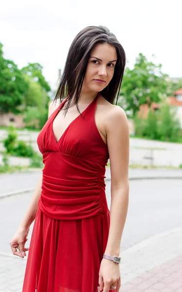 빨간 드레스를 입은 아름다운 소녀가 거리에서 포즈를 취하는 모습 — 스톡 사진