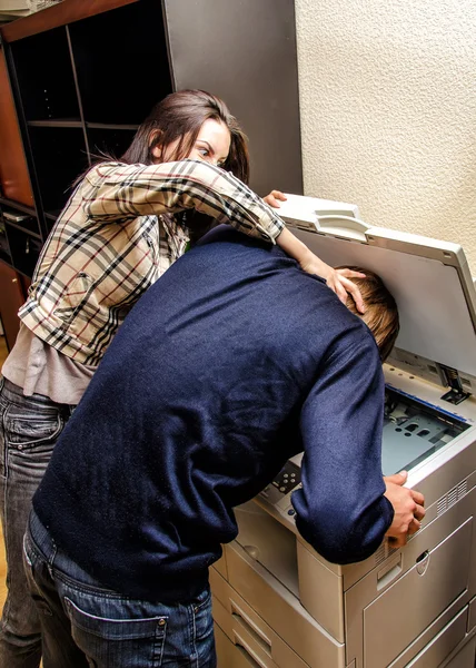 Офисная месть: женщина пытается засунуть мужчину в копировальную машину — стоковое фото