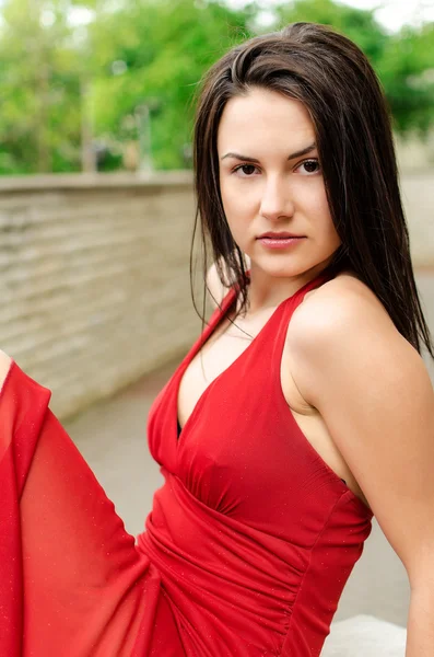 Mooi meisje in rood jurk poseren op de straat Stockfoto