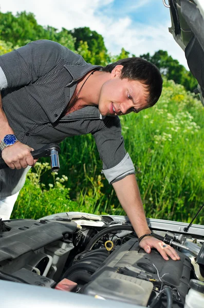Mladý muž opravit rozbité auto s Nástrčný klíč. — Stock fotografie