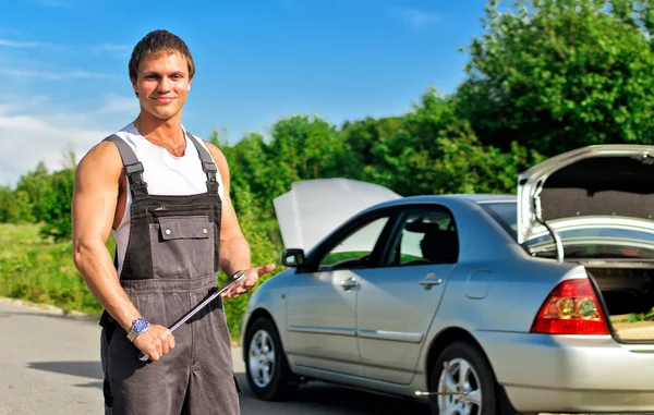 Schöner Mechaniker auf einer Straße in der Nähe des kaputten Autos — Stockfoto