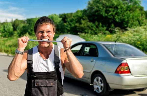 Mad mechanic near a broken car on the road. — Stock Photo, Image