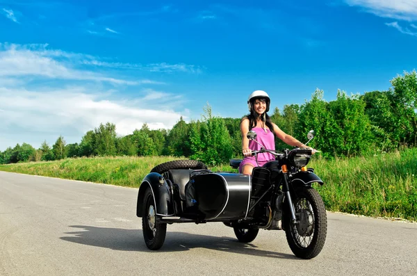 Mooie vrouw rijden op een motorfiets met een zijspan. — Stockfoto