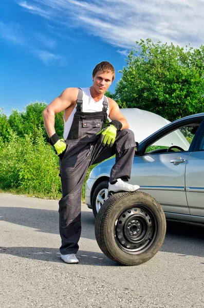 Mecánico guapo parado en un neumático en la carretera —  Fotos de Stock