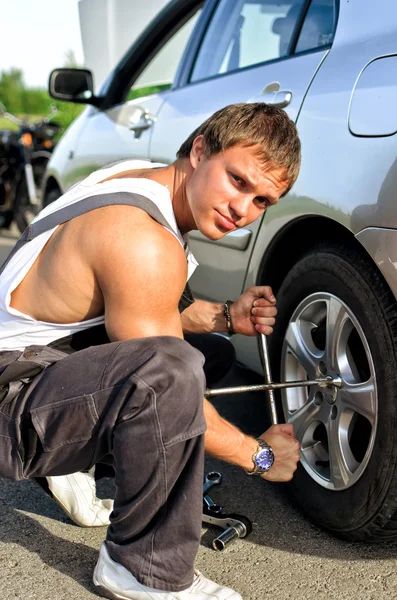 Mecânico que fixa um pneu em uma estrada — Fotografia de Stock