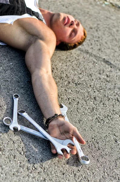 Втомлена механічна кладка на дорозі з гайковим ключем з нержавіючої сталі в руці — стокове фото