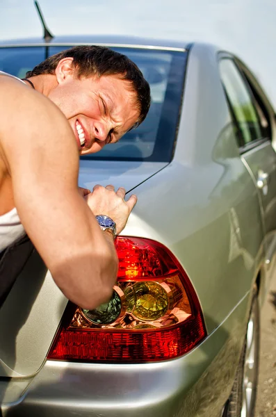Yakışıklı adam iterek kırık araba — Stok fotoğraf