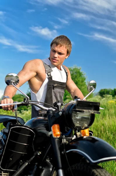 Bello uomo in una tuta da boilersuit in piedi vicino alla moto . — Foto Stock