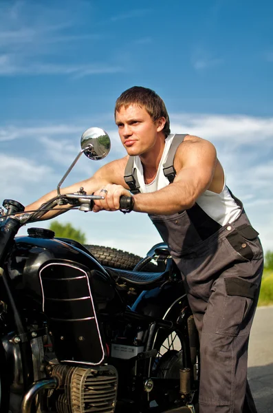 Charmant homme en tenue de chaudière roulant une moto . — Photo