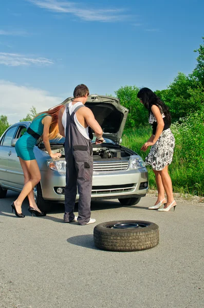 Механик и две девушки рядом со сломанной машиной на дороге — стоковое фото