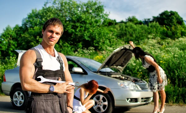 Portrait of a hadsome mechanic with two women on a background — Stock Photo, Image