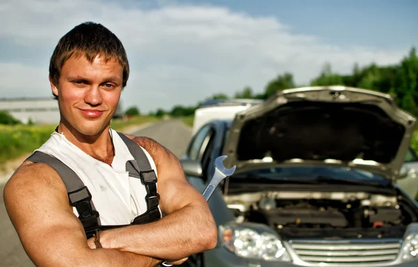 Portret hadsome mechanik z uszkodzonego samochodu na tle — Zdjęcie stockowe