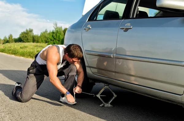 Mechanic lifting a car with jack-screw — Stock Photo, Image