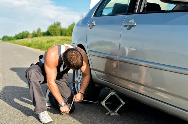 Mechanic lifting a car with jack-screw — Stock Photo, Image