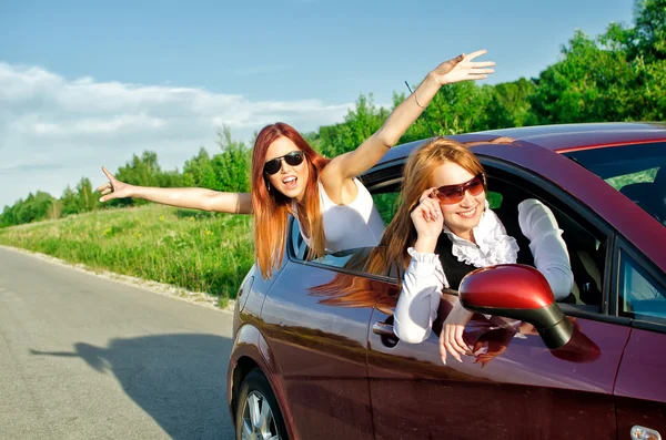 Две довольно счастливые девушки в машине. Концепция беззаботного дорожного путешествия — стоковое фото