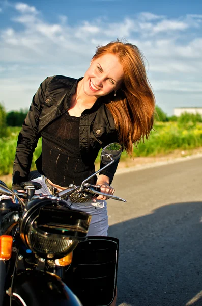 Kızıl saçlı kız bir yolda bir motosiklet üzerinde gülümseyen — Stok fotoğraf