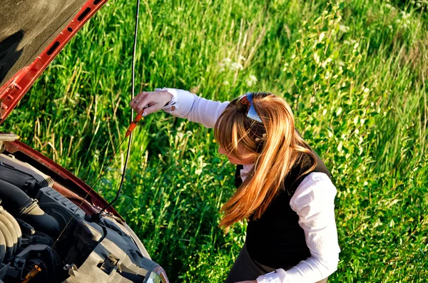 Menina mede o nível de óleo em um carro — Fotografia de Stock