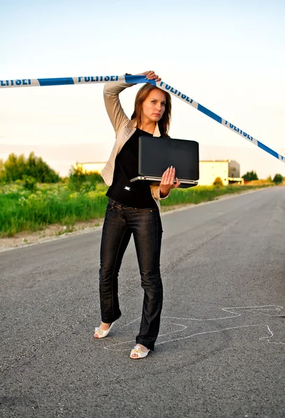 Mladý kriminalista s notebookem přes policejní pásku — Stock fotografie