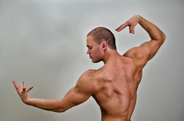 Muskulöser Bodybuilder posiert. auf grauem Hintergrund. — Stockfoto