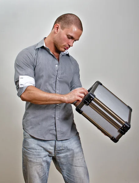 Trendy male holding suitcase. On grey background. — Stock Photo, Image