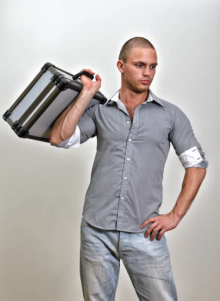 Trendy male holding suitcase. On grey background. — Stock Photo, Image
