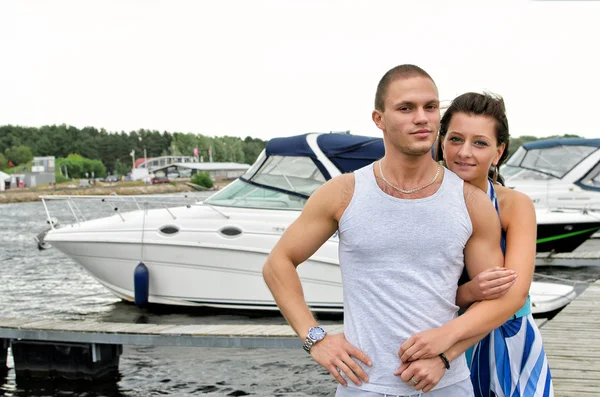 Mladý pár proti molo s čluny. — Stock fotografie