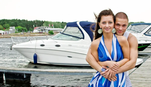 Junges Paar mit Booten gegen Seebrücke. — Stockfoto
