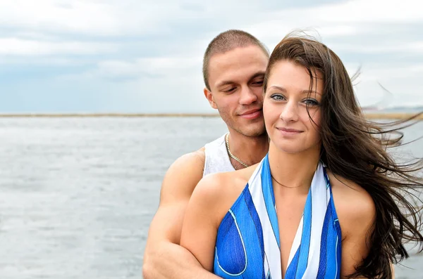 Jonge mooie paar tegen blauwe zee. — Stockfoto