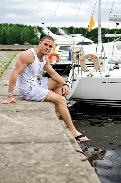 Привабливий м'язистий чоловік сидить біля яхти — стокове фото