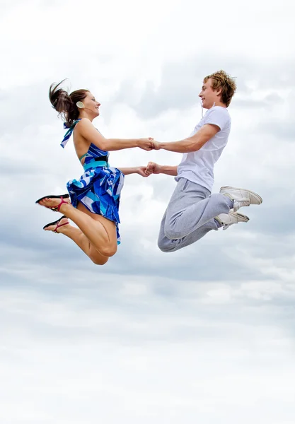 Портрет счастливой молодой пары, прыгающей в воздух на фоне неба . — стоковое фото