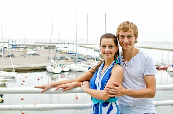 Attractive couple against pier with yachts. — Stock Photo, Image