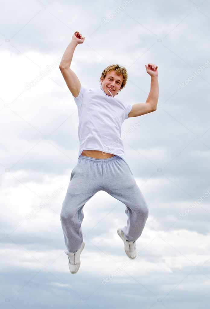 Portrait of a happy young man jumping in air against sky.