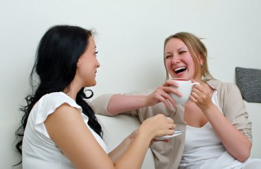 Two women friends chatting over coffee at home clipart