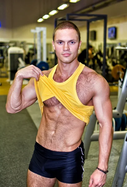 Beau bodybuilder montrant son corps dans un gymnase — Photo