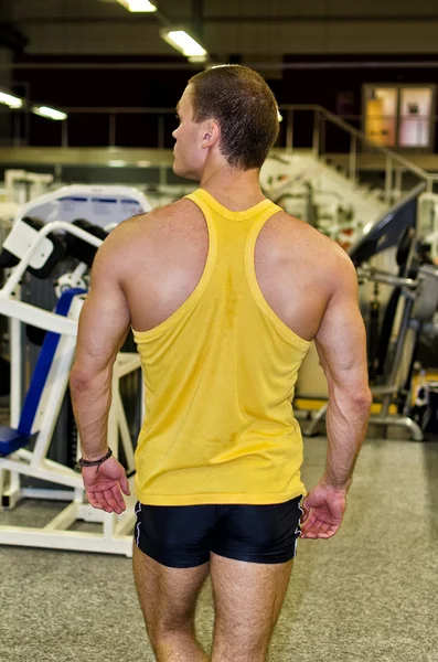 Bodybuilder in a gym from the back — Stock Photo, Image