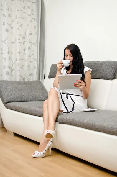 Brunette girl with tablet pc on the sofa. — Stok fotoğraf