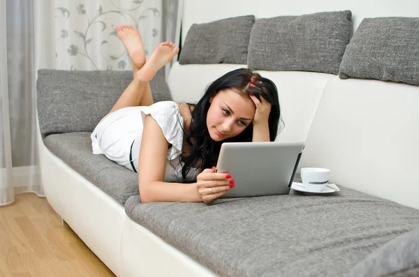 Brunette fille avec tablette PC sur le canapé . — Photo