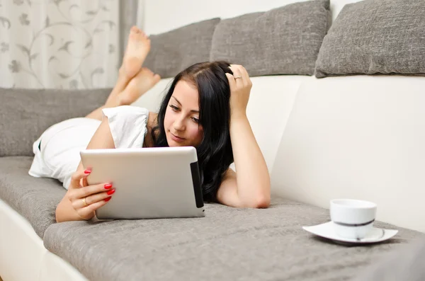 Brunette girl with tablet pc on the sofa. — Stok fotoğraf