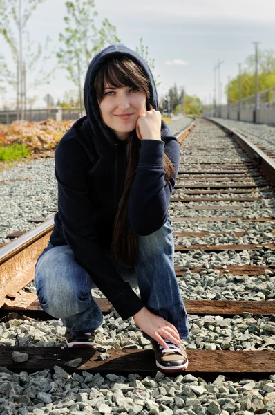 Pige sidder i jernbanen - Stock-foto
