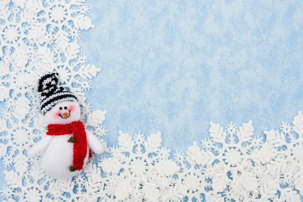 Copos de nieve con muñeco de nieve haciendo un borde sobre un fondo azul —  Fotos de Stock