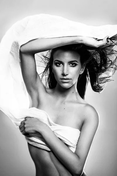 Jovem moda modelo grego segurando um tecido preto branco soprado pelo vento isolado estúdio tiro — Fotografia de Stock