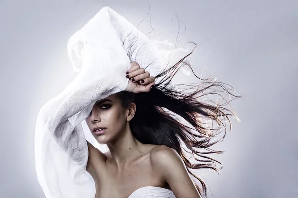 Young fashion Greek model holding a white black fabric blown by the wind isolated studio shot — Stok fotoğraf