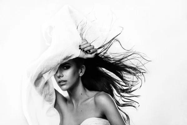 Young fashion Greek model holding a white black fabric blown by the wind isolated studio shot — Stok fotoğraf
