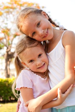 Two sisters near a tree clipart