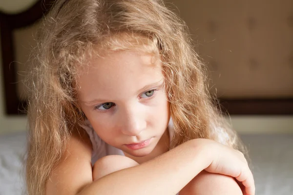 Porträt eines traurigen Mädchens, das auf einem Bett sitzt — Stockfoto