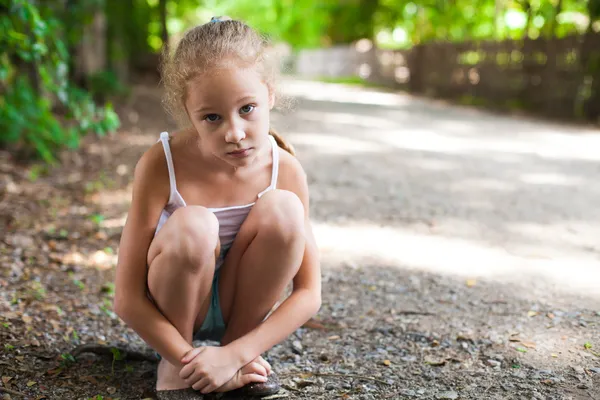 Yolun oturan üzgün küçük kız — Stok fotoğraf