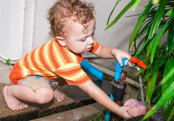 Ребенок наливает воду из крана — стоковое фото