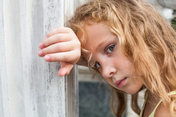 Szomorú, kicsi lány, a háttérben egy régi fal — Stock Fotó