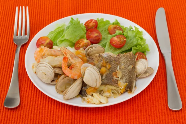 Тушеная рыба с салатом на белой тарелке — стоковое фото